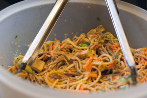 Summer time peanut noodles with tofu topping in a plastic bowl